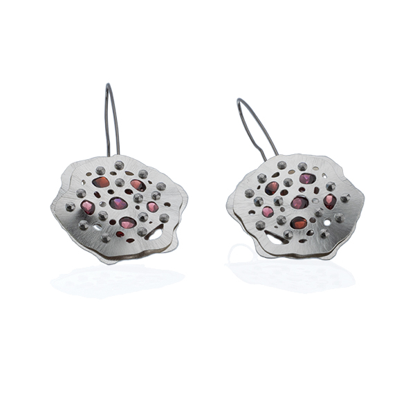 front angled view of a pair of earrings with faceted garnets tension set into the argentium sterling silver